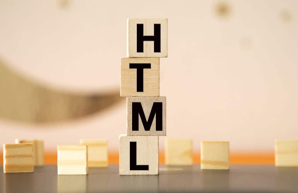 Close-up of wooden blocks stacked to spell 'HTML' on a wooden table.