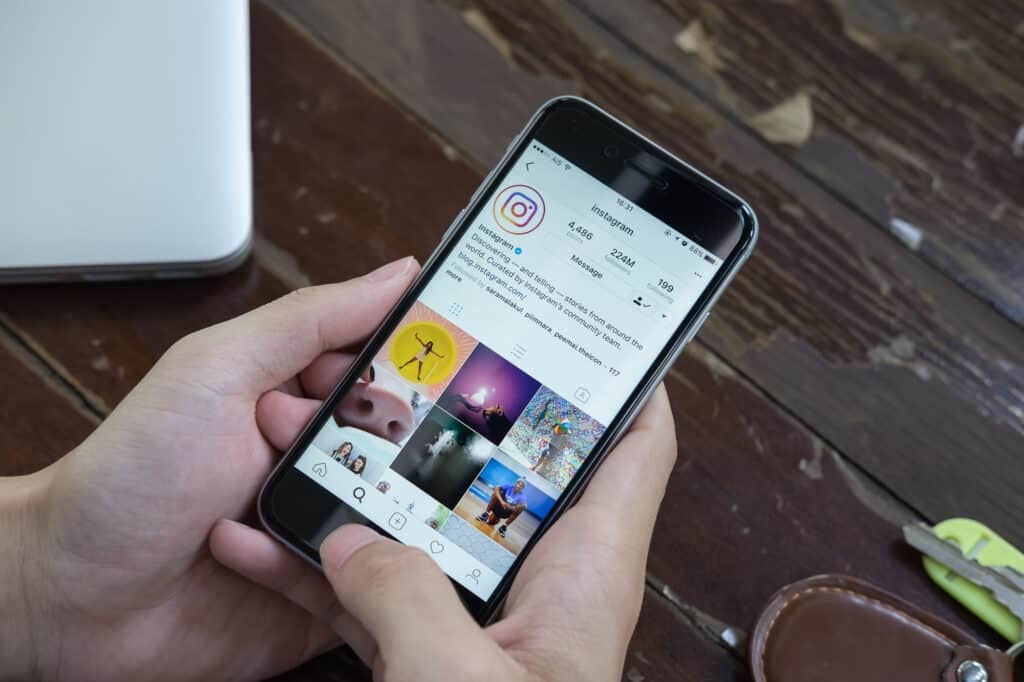 A man's hand holding an iPhone with the new Instagram logo.