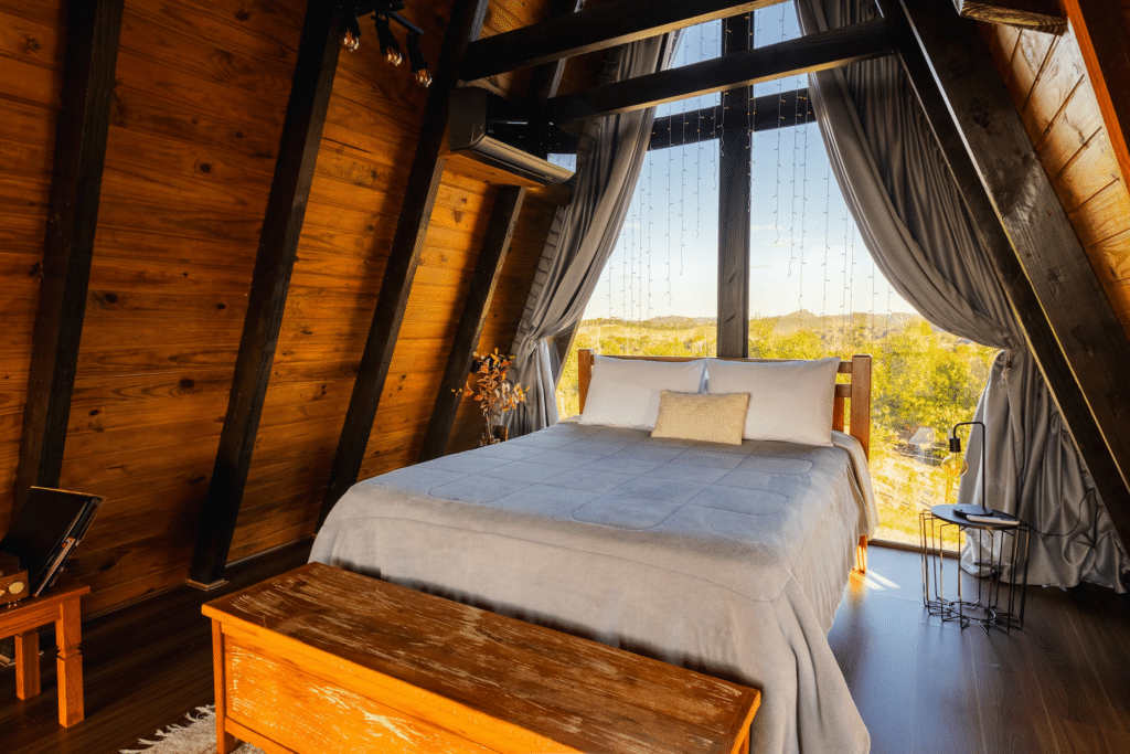 Airbnb bedroom in A-frame wooden cabin in the woods with view of mountains out of the window.