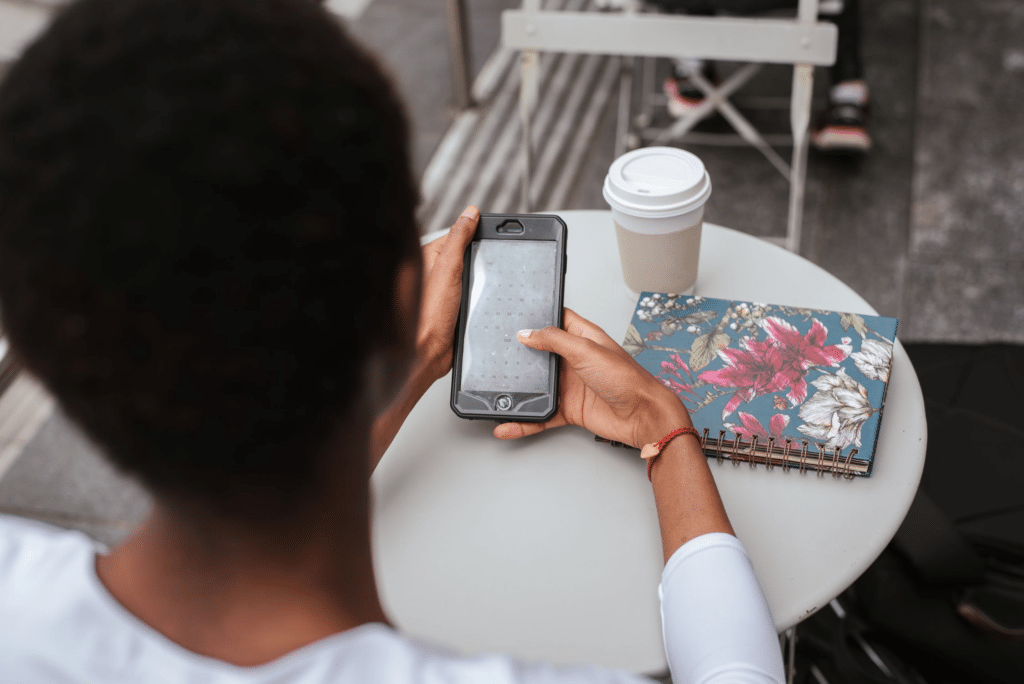 Woman messaging on her phone while sitting at a table at a cafe.
