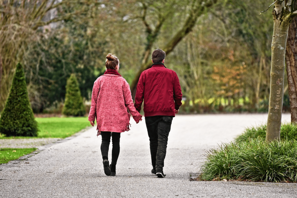 Couple walking through a park together holding hands.