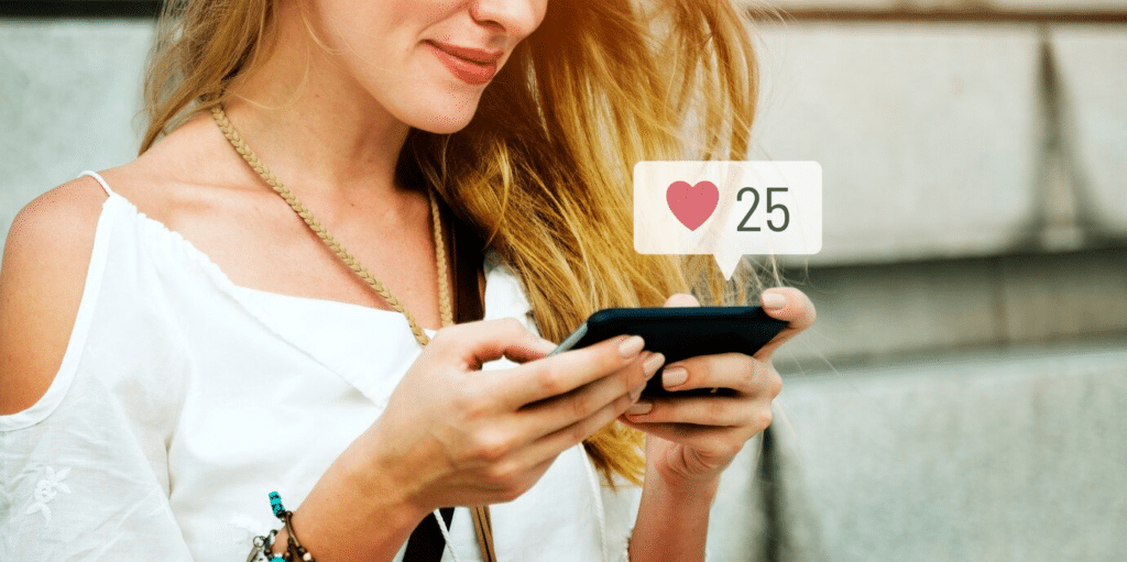 An attractive lady checks her phone, which displays 25 hearts.