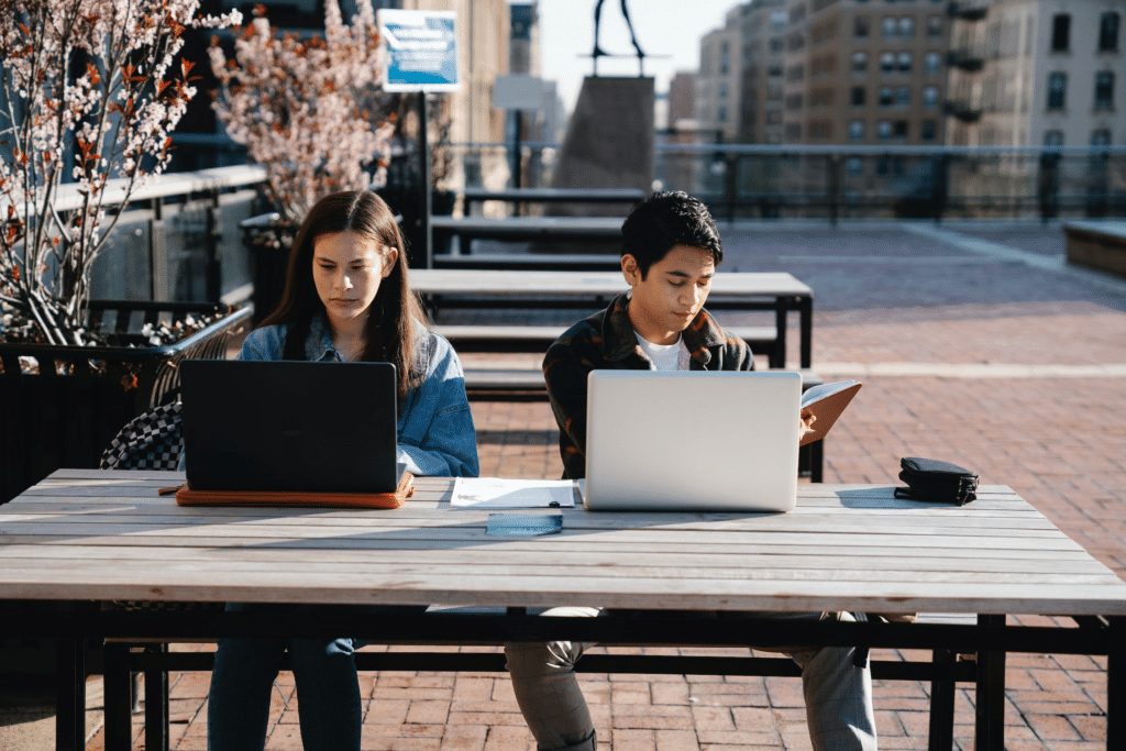 Man and woman sitting together at a table on their laptops.