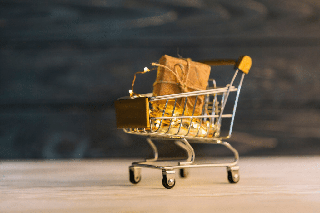 A close-up of a small shopping cart with a gift box inside, signifying Amazon ecommerce shopping.