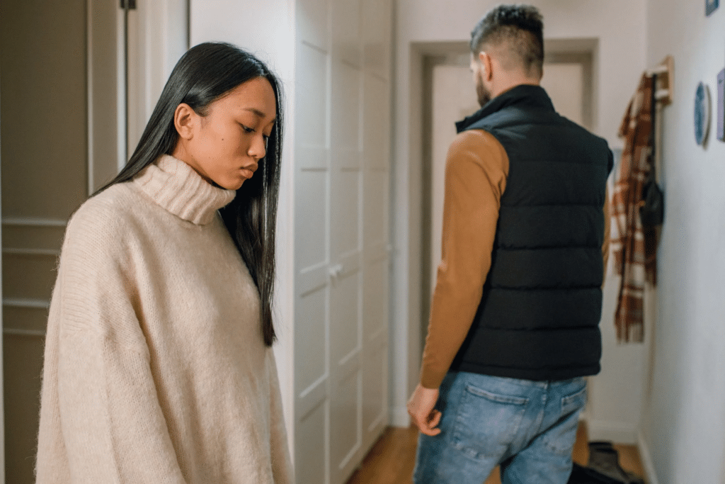 A couple at the end of an argument, where the girl looks sad and the man turns away towards the door.