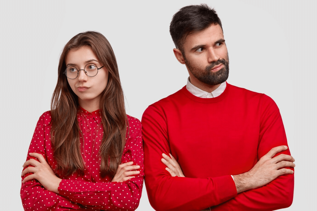Man and woman standing with their arms crossed looking disappointed.