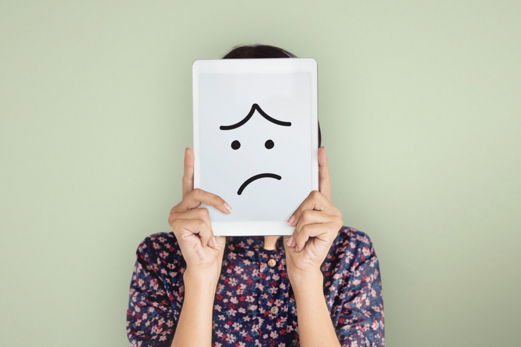 No Likes on Coffee Meets Bagel: A young lady holds a tablet in front of her face with a sad face drawn on it.