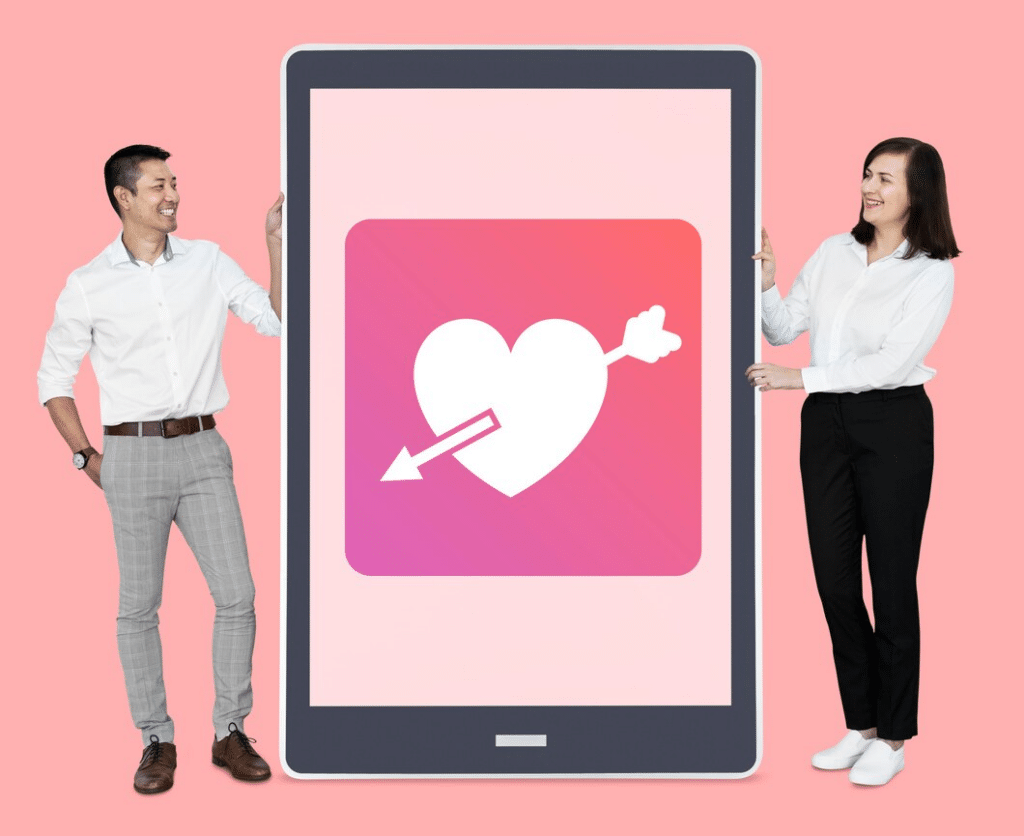 A professional man and woman each stand on the side of a large tablet with a Cupid heart image on it.